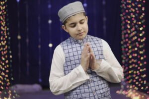 Naat and Spiritual Harmony | Muhammad Anas Nazeer in a blue vest against a bokeh light background.